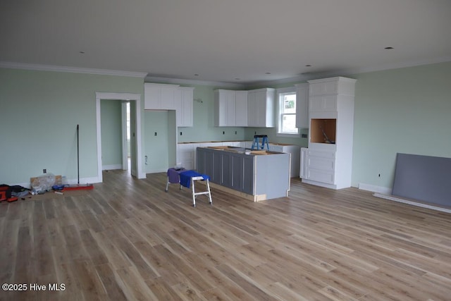 kitchen with white cabinetry, ornamental molding, light wood-style floors, and a kitchen island