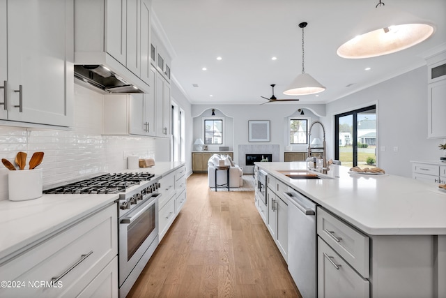 kitchen with sink, pendant lighting, a kitchen island with sink, white cabinets, and appliances with stainless steel finishes