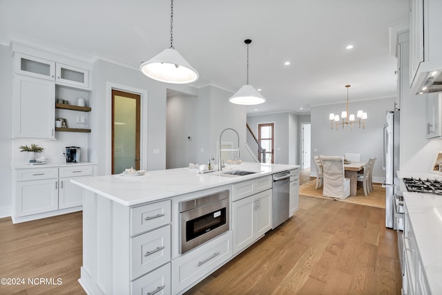 kitchen with appliances with stainless steel finishes, white cabinetry, pendant lighting, and an island with sink