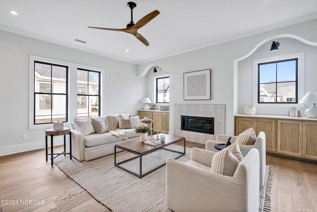 living room with a healthy amount of sunlight, crown molding, and light hardwood / wood-style floors