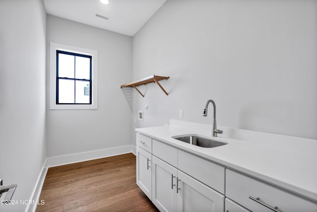 laundry area with washer hookup, light hardwood / wood-style floors, cabinets, and sink