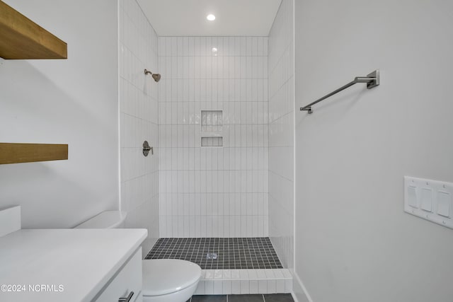 bathroom with a tile shower, vanity, and toilet