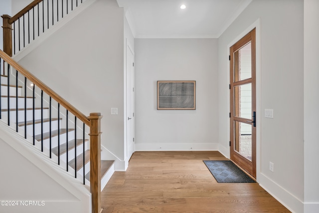 foyer entrance with light wood-type flooring and crown molding