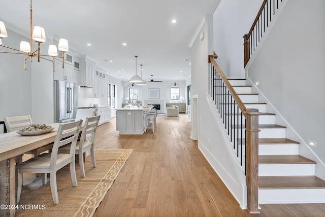 dining area with ceiling fan with notable chandelier and light hardwood / wood-style flooring