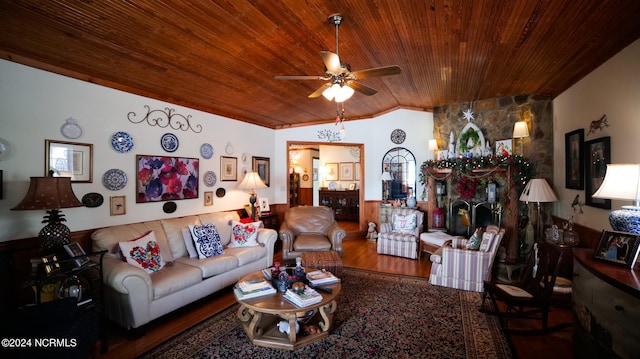 living room with lofted ceiling, ceiling fan, wood ceiling, a stone fireplace, and dark hardwood / wood-style flooring