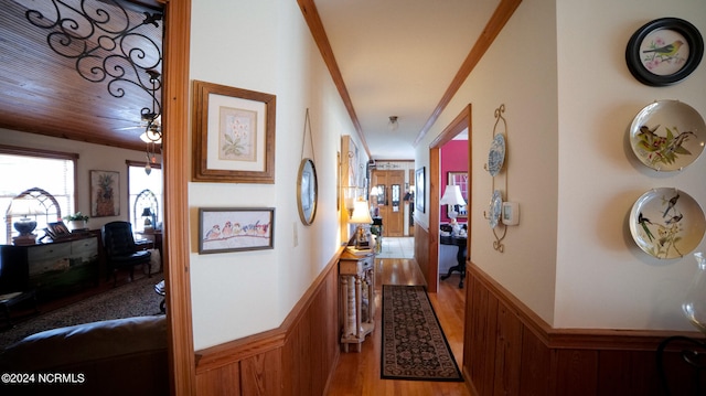 corridor with light wood-type flooring and crown molding