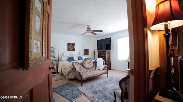 bedroom featuring ceiling fan, a textured ceiling, and light carpet