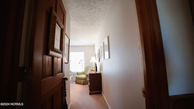 hallway featuring a textured ceiling and light carpet