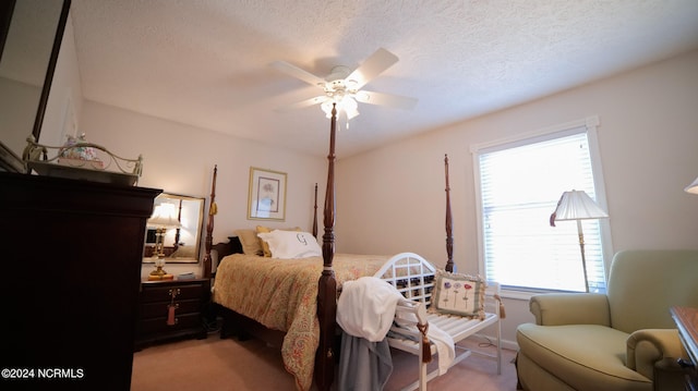 bedroom featuring light colored carpet, ceiling fan, and a textured ceiling