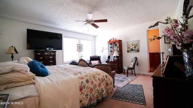 carpeted bedroom with ceiling fan and a textured ceiling