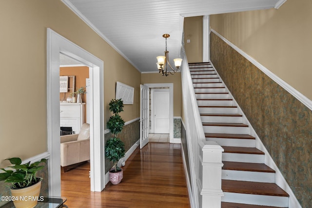 stairway featuring an inviting chandelier, ornamental molding, and dark hardwood / wood-style floors