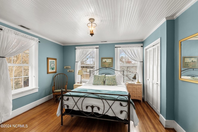 bedroom with multiple windows, hardwood / wood-style floors, and a closet