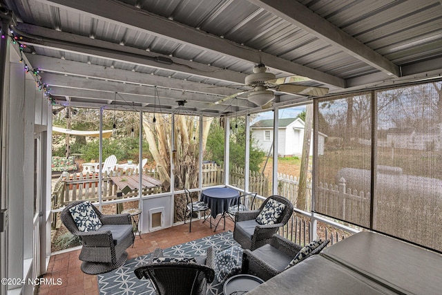 sunroom with ceiling fan and beamed ceiling