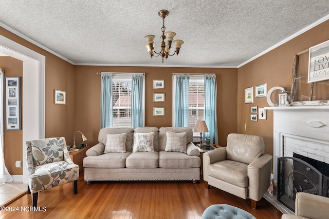 living room with an inviting chandelier, a fireplace, a textured ceiling, crown molding, and dark hardwood / wood-style floors