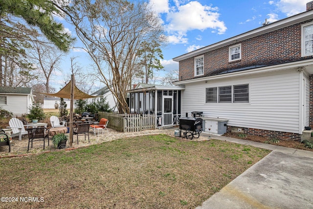 back of property featuring a yard, a patio area, and a sunroom