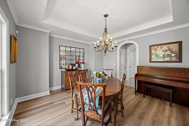 4441 Lagan Cir, Winterville, NC 28590 - dining area featuring a tray ceiling, a chandelier, light wood-style flooring, ornamental molding, and arched walkways