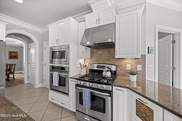 4441 Lagan Cir, Winterville, NC 28590 - kitchen with under cabinet range hood, appliances with stainless steel finishes, arched walkways, white cabinets, and backsplash