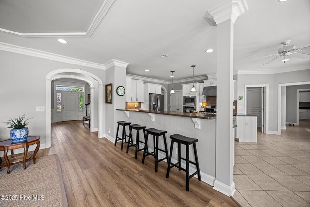 4441 Lagan Cir, Winterville, NC 28590 - kitchen with appliances with stainless steel finishes, under cabinet range hood, recessed lighting, a kitchen breakfast bar, and arched walkways