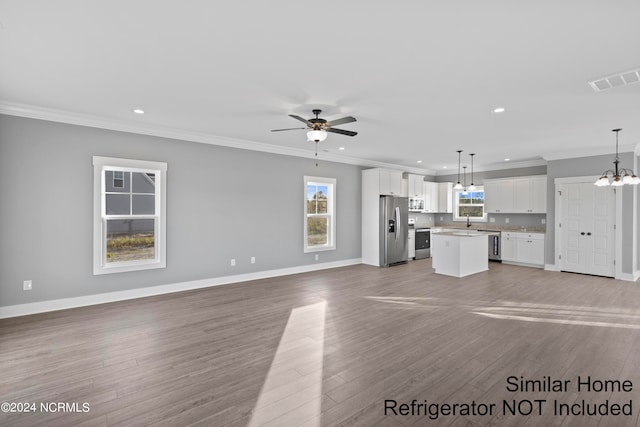 unfurnished living room with light wood-type flooring, a wealth of natural light, and ornamental molding