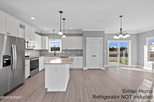 kitchen featuring light wood-type flooring, stainless steel appliances, decorative light fixtures, and white cabinets