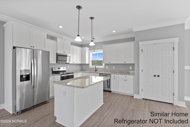 kitchen featuring light hardwood / wood-style flooring, white cabinets, stainless steel appliances, pendant lighting, and ornamental molding