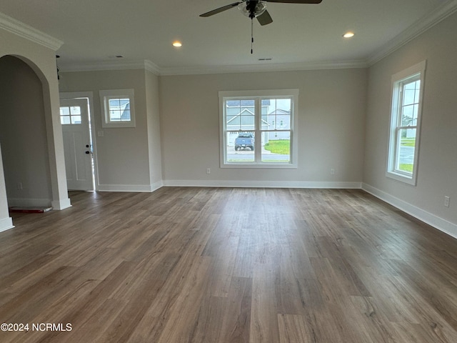 unfurnished living room with ornamental molding, ceiling fan, wood-type flooring, and a wealth of natural light