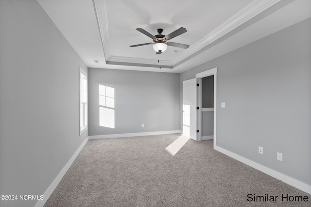 carpeted spare room with a raised ceiling, crown molding, and ceiling fan