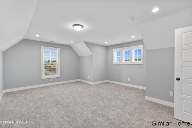 bonus room with light colored carpet, a healthy amount of sunlight, and lofted ceiling