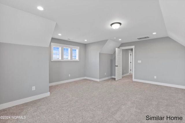 additional living space featuring light carpet and vaulted ceiling