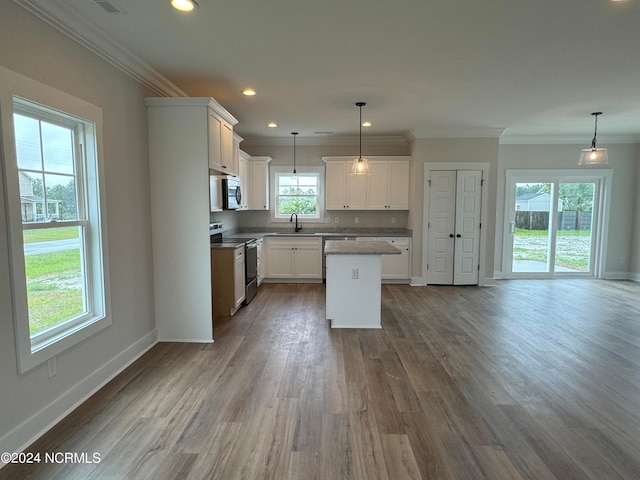 kitchen with electric stove, sink, a center island, white cabinetry, and hardwood / wood-style flooring