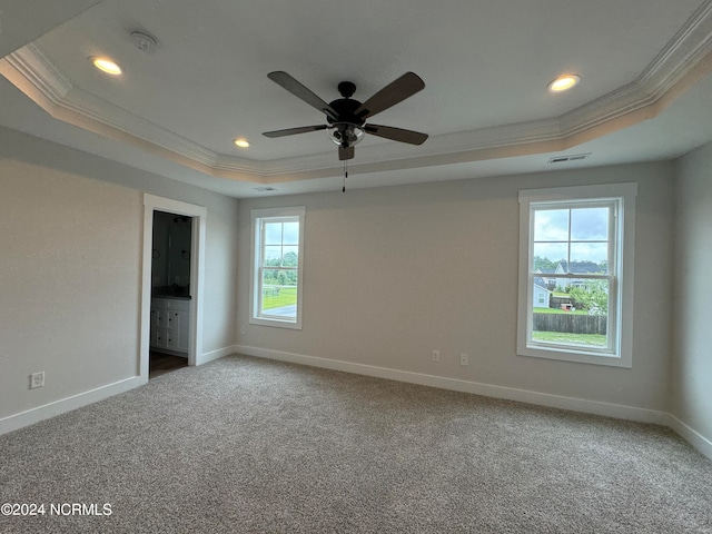 carpeted empty room with ceiling fan, a tray ceiling, and ornamental molding