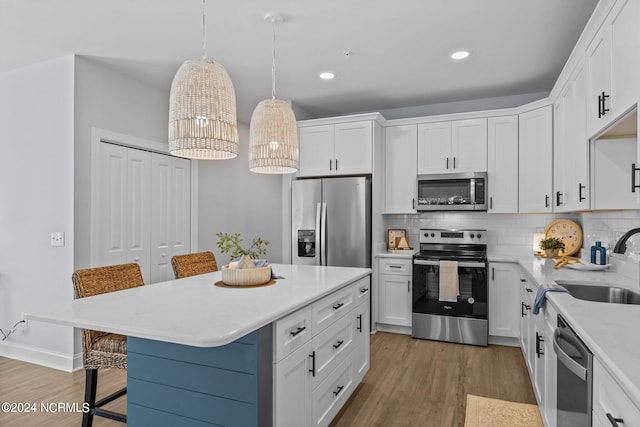 kitchen with a breakfast bar, appliances with stainless steel finishes, white cabinetry, and hanging light fixtures