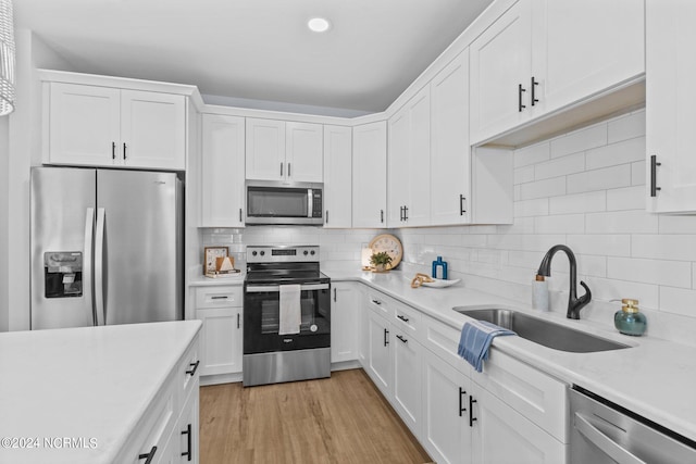 kitchen with white cabinetry, sink, tasteful backsplash, appliances with stainless steel finishes, and light wood-type flooring