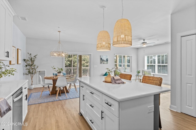 kitchen with a wealth of natural light, white cabinets, and hanging light fixtures