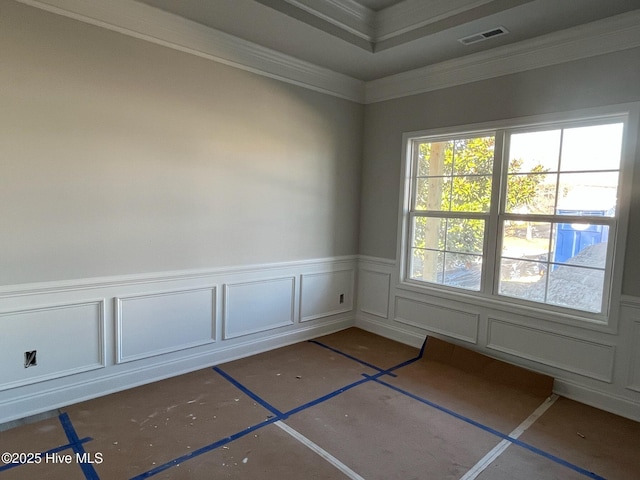 empty room with a wainscoted wall, a decorative wall, visible vents, and crown molding