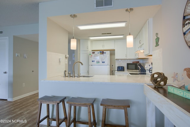 2000 New River Inlet Rd Unit 3309, North Topsail Beach, NC 28460 - kitchen with kitchen peninsula, white fridge, hanging light fixtures, backsplash, and white cabinetry