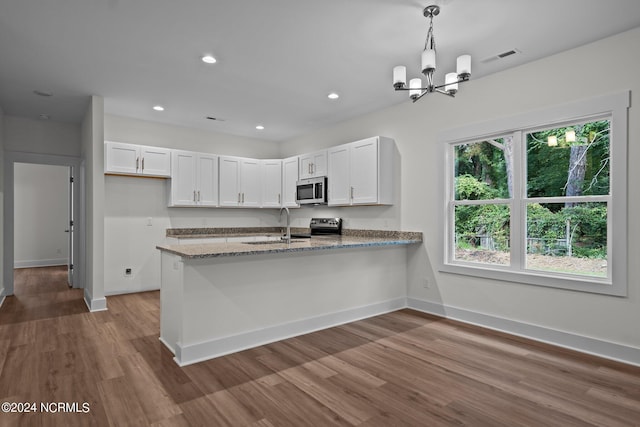 kitchen featuring hanging light fixtures, white cabinets, light wood-type flooring, stone counters, and appliances with stainless steel finishes