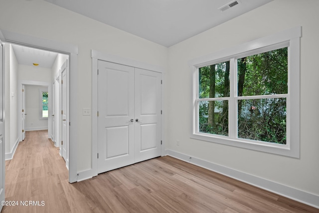 unfurnished bedroom with multiple windows and light hardwood / wood-style floors