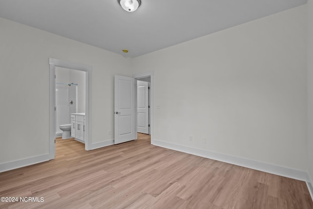 unfurnished bedroom featuring ensuite bathroom and light wood-type flooring