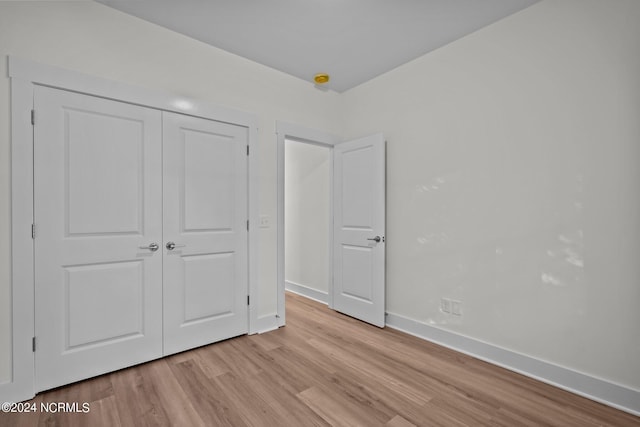 unfurnished bedroom with a closet and light wood-type flooring