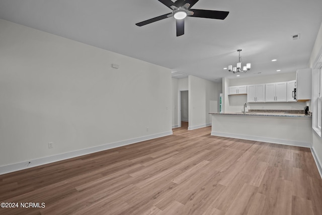 unfurnished living room with light hardwood / wood-style floors, sink, and ceiling fan with notable chandelier