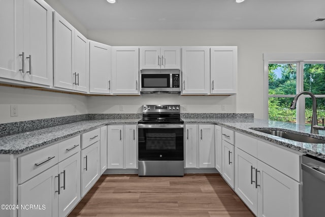 kitchen with white cabinetry, light hardwood / wood-style floors, appliances with stainless steel finishes, and sink