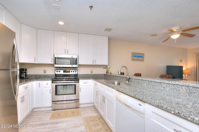 kitchen with stainless steel appliances, ceiling fan, white cabinetry, light wood-type flooring, and sink