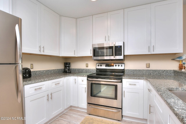 kitchen featuring white cabinetry, light hardwood / wood-style floors, light stone counters, and stainless steel appliances