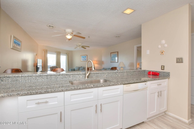 kitchen featuring ceiling fan, sink, light stone counters, white cabinets, and white dishwasher