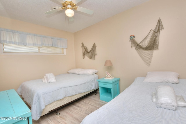 bedroom with a textured ceiling, ceiling fan, and light wood-type flooring