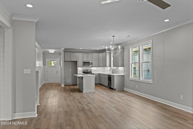 kitchen featuring ceiling fan with notable chandelier, gray cabinetry, hardwood / wood-style floors, a center island, and appliances with stainless steel finishes