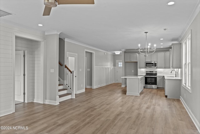 kitchen featuring light hardwood / wood-style flooring, stainless steel appliances, ceiling fan with notable chandelier, a center island, and ornamental molding