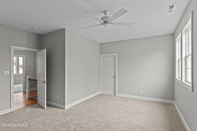 carpeted spare room featuring ceiling fan and a healthy amount of sunlight