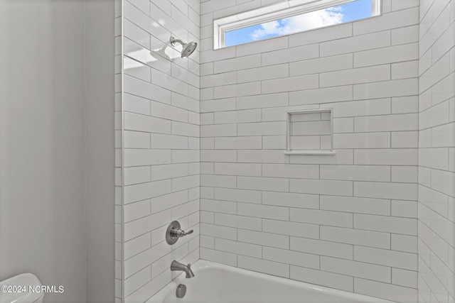 bathroom featuring tiled shower / bath and toilet